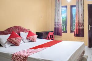 a bedroom with a bed with red and white pillows at OYO 93332 Kharis Home Stay in Jayapura