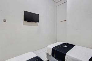 a room with a bed and a tv on a wall at Capital O 93361 Dynasty Inn Syariah in Pekalongan