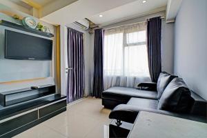 a living room with a couch and a flat screen tv at Hotel O Apartement Grand Sentraland By Rai Property in Jaken 1