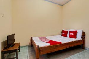 a bedroom with a bed with red pillows and a television at Hotel O Pondok Wisata Sekar KemuningNearWonogondang Camp ( Bumi Perkemahan Wonogondang ) in Yogyakarta +19 photos