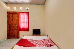 a bedroom with a bed and a window with a red curtain at Hotel O Pondok Wisata Sekar KemuningNearWonogondang Camp ( Bumi Perkemahan Wonogondang ) in Yogyakarta