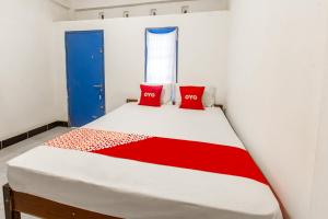 a bedroom with a bed with two red pillows at Hotel O Kawi Homestay in Praya