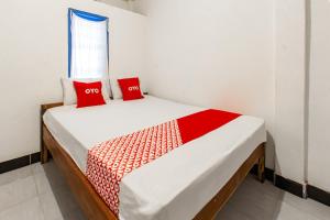 a bed in a room with two red pillows on it at Hotel O Kawi Homestay in Praya +18 photos