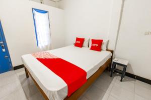 a bedroom with a bed with red pillows on it at Hotel O Kawi Homestay in Praya