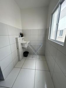 a white bathroom with a sink and a window at Casa em Parnaíba 6km praia in Parnaíba