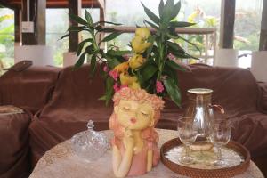a doll sitting on a table with glasses and a vase at Atash Eco Village Homestay Van Hoi in Quân Khê +149 photos