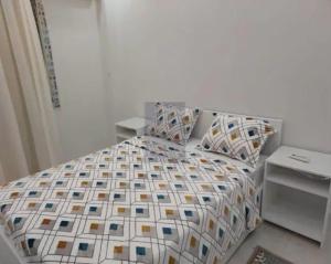 a white bedroom with a bed with a patterned comforter at Rence Luxury Apartment in Cairo