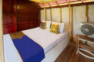 a bed in a small room with a fan at Hotel O Bale Kertiasih Near SMPN Satap 4 GANGGA in Labuan Lombok