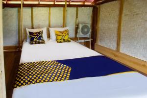 two beds with yellow and blue pillows in a room at Hotel O Bale Kertiasih Near SMPN Satap 4 GANGGA in Labuan Lombok