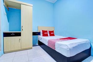 a small bedroom with a bed with red pillows at OYO 93209 Guest House Cemara 3 in Tegal