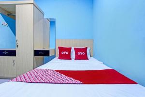 a large bed with two red pillows on it at OYO 93209 Guest House Cemara 3 in Tegal