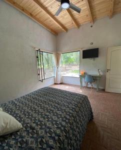 Un dormitorio con una cama con ventilador de techo y una ventana. en La Casa De Los Pinos, en Casa Grande