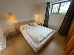 a bedroom with a bed with white sheets and a window at Charmante villa bord de mer avec parking et WiFi, proche plage et commerces - FR-1-22-377 in La Tranche-sur-Mer