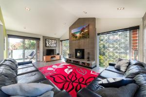 sala de estar con sofá y alfombra roja en Double Bays Beauty - Stay Waiheke, en Waiheke Island