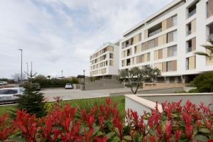 a building with red flowers in front of a parking lot at Luxury Apartment "Ema", sea view in Split