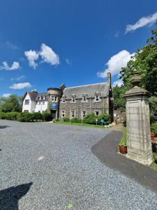 an old house with a stone monument in front of it at Forest Valley Holiday Home in Ballantrae