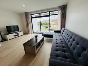 a living room with a couch and a tv at Lower Hutt Central Brand New 3 bedroom 2 Bath Spacious House Balcony Private garage in Lower Hutt