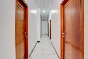 a hallway with two wooden doors and a tile floor at Hotel O Muula Homestay Syariah in Pati