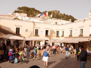una folla di persone che camminano per strada con un edificio di Guest House La Piazzetta a Capri