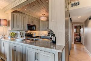 una cocina con armarios blancos y encimeras de mármol en Oceans Of Amelia Condo, en Fernandina Beach