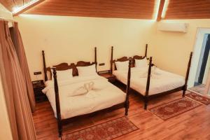a bedroom with two beds with white sheets at Nidhivann- A Wellness Retreat Resort Pench in Khawāsa