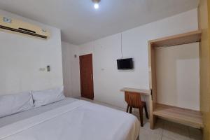 a white bedroom with a bed and a desk at Hotel O Wira Residensia Syariah in Medan