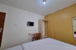 a bedroom with a bed and a tv on the wall at Hotel O Wira Residensia Syariah in Medan