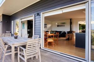 a sliding glass door opens up to a patio with a table and chairs at Ruru House in Auckland