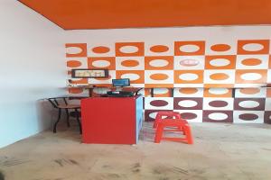 a room with a wall with a table and a red stool at Hotel O Kamboja Homestay Syariah in Delitua