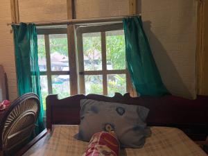 a bedroom with a bed and a window with green curtains at Mamasa Local House in Mamasa