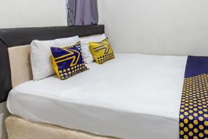 a bed with four pillows on top of it at Hotel O Penginapan Melati Tanjung Near Kantor Pengamat Pengairan Tanjung in Papak