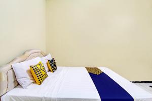 a bed with three pillows on top of it at Hotel O Juan Guest House in Purwokerto