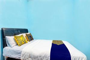 a bed with yellow and blue pillows on it at Hotel O Juan Guest House in Purwokerto
