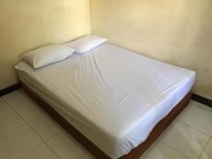 a bed with white sheets and pillows in a room at OYO Life 93525 Griya Wafira Trenggalek Syariah in Trenggalek