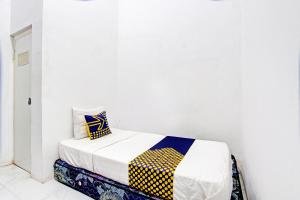 a bed in a room with a white wall at Hotel O Agus Kostel SyariahNearWisata Agro Jollong in Gembong +21 photos