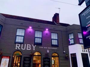 布莱顿霍夫OYO Ruby Pub & Hotel的一座砖砌建筑,上面有紫色的灯