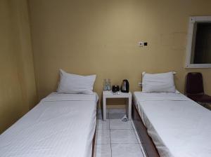 a room with two beds and a table with a phone at OYO 93411 Syariah Hotel Tomborang in Karema +22 photos