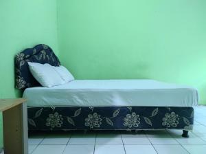 a bed in a room with a blue wall at OYO 93411 Syariah Hotel Tomborang in Karema