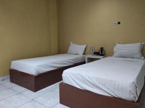 two beds sitting next to each other in a room at OYO 93411 Syariah Hotel Tomborang in Karema