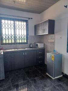 a kitchen with blue cabinets and a sink and a window at Exclusive-View Lodge in Akropong