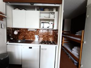 a small kitchen with white cabinets and a stove at Résidence Chalmettes - Studio 2/4 personnes - Skis aux pieds MAE-9074 in Montgenèvre