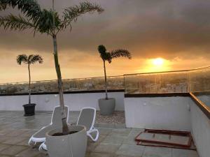 a balcony with two chairs and palm trees and the sunset at Luxurious Apt with Rooftop Pool in Dakar