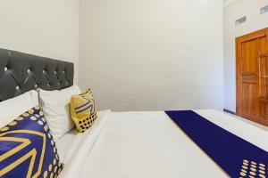 Schlafzimmer mit einem Bett mit blauen und gelben Kissen in der Unterkunft Hotel O Triple N Homestay in Sidoarjo