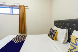 Schlafzimmer mit einem Bett mit einem schwarzen Kopfteil und Kissen in der Unterkunft Hotel O Triple N Homestay in Sidoarjo