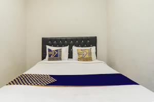 ein Bett mit blau-weißen Laken und Kissen in der Unterkunft Hotel O Triple N Homestay in Sidoarjo