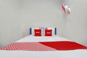 a bed with two red pillows and a red blanket at Hotel O Homestay Bambu Oerip Syariah in Yogyakarta