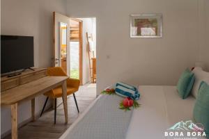 a living room with a desk and a television at Matira Beach House in Bora Bora