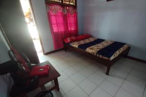 una piccola camera da letto con un letto e una sedia di Hotel O Dannis Homestay Near Musholla Al Istiqomah Terawangan a Lombok
