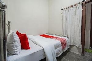 a bedroom with a bed with red and white pillows at Hotel O Hidayah Homestay Syariah in Sidoarjo