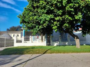 una casa con una valla blanca y un árbol en Swartkops Cann-a-bee Air B&B, en Gqeberha